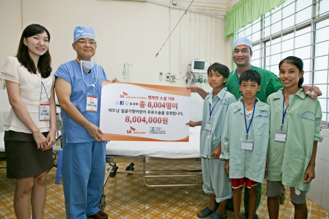 Officials of SK Telecom and Seoul National University Bundang Hospital pose with Vietnamese children after donating 8 million won to help treat children with facial deformities in Vietnam. The company said a total of 3,000 Vietnamese children received free surgical operation to treat the disability.    (SK Telecom)