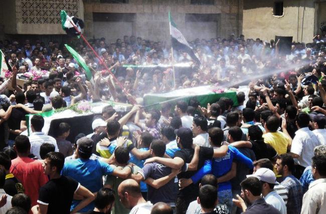 This citizen journalism image provided by Shaam News Network SNN, purports to show an anti-Syrian regime man (center), spraying water over mourners to cool them from the heat as they carry the coffins of those killed by the Syrian forces shelling in Daraa on Tuesday.
(AP-Yonhap News)