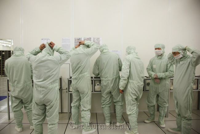 Employees put on clean suits at Semiconductor Manufacturing International Corp. in Shanghai.  Bloomberg