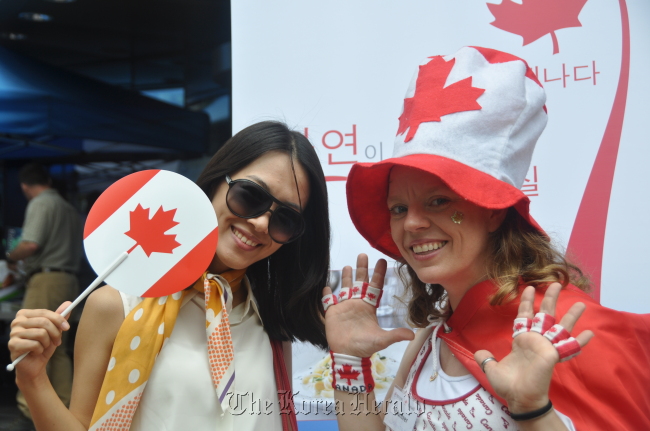 People pose outside the Canadian Embassy on Sunday, as they wait for samples of Canadian maple syrup candy, beer and beef as part of the Canadian Chamber of Commerce in Korea Canada Day Celebration. Canadian Chamber of Commerce in Korea