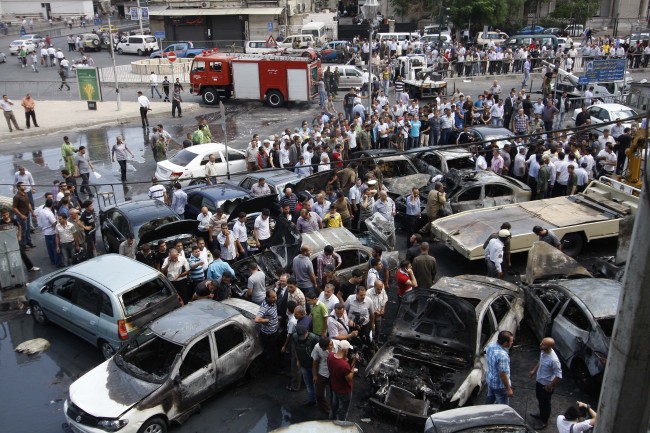 Syrians inspect burned cars at the site of a blast in the Syrian capital Damascus on June 28.   (AP-Yonhap News)