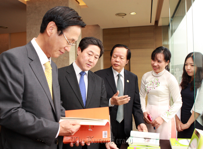 KB Kookmin Bank chief executive Min Byong-deok (left) takes a look at the Korean textbooks in four languages ― Vietnamese, Mongolian, Indonesian and Kazakh ― with Rep. Yoo Ki-june (second from left) and Vietnamese Ambassador Tran Trong Toan (third from left) at a ceremony to celebrate the publication Tuesday in a Seoul hotel. KB Kookmin and the Korea Foundation jointly developed the textbooks which will be provided to universities in the four countries for Korean language education.  (KB Kookmin Bank)