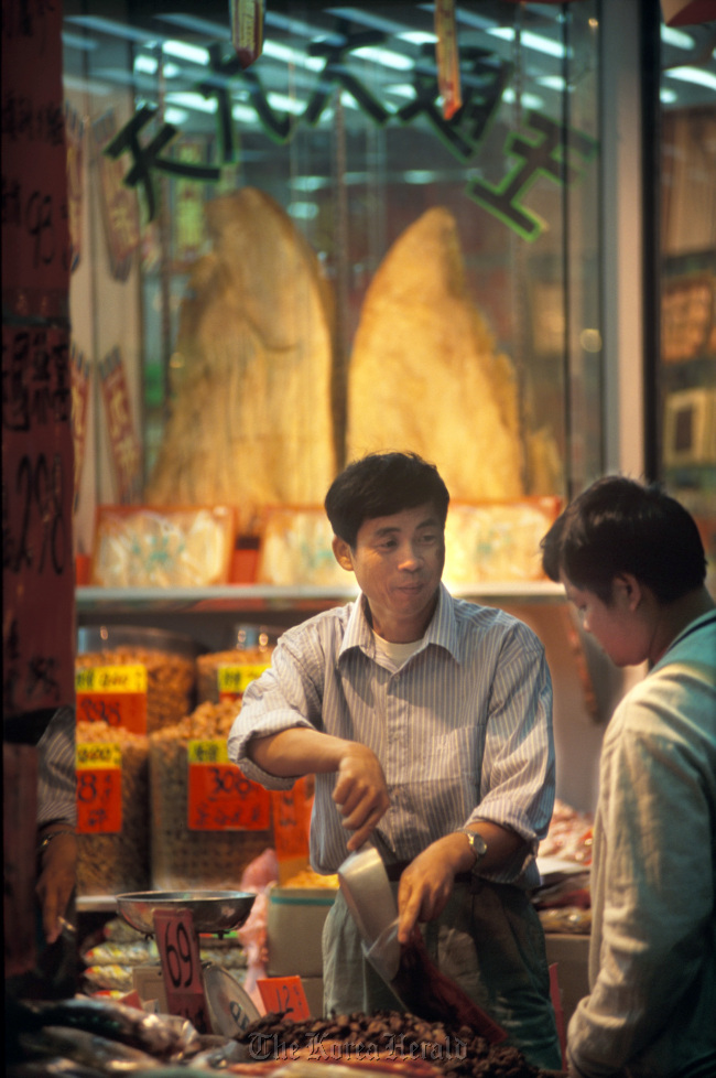 A salesman at a dry goods shop selling shark fins helps a customer in Hong Kong. Bloomberg