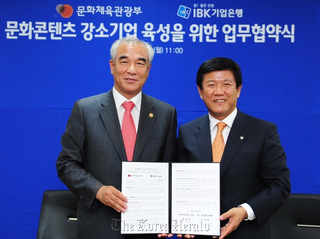 Culture Minister Choe Kwang-shik (left) and IBK president & CEO Cho Jun-hee pose for photo after signing an memorandum of understanding for supporting local content developers with 138 billion won worth fund at the Culture Ministry in Seoul, Monday. Culture Ministry
