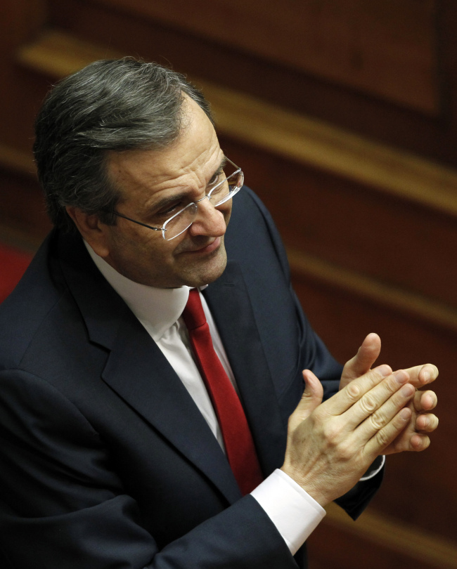 Greek Prime Minister Antonis Samaras applauds at the Parliament after winning a vote of confidence in Athens, late Sunday.  AP-Yonhap News