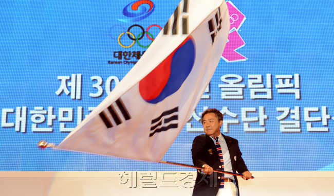 11일 오후 서울 송파구 방이동 올림픽홀에서 열린 2012 런던올림픽 선수단 결단식에서. 이기흥 대표선수단장이 박용성 대한체육회장에게 전달받은 단기를 흔들고 있다./ 안훈기자 rosedale@ 2012.07.11