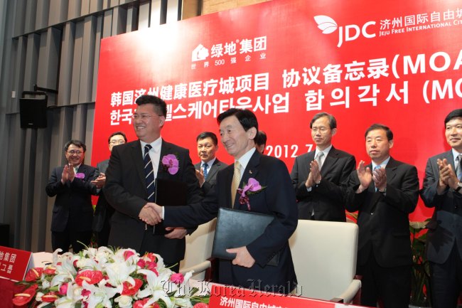 Byon Jong-il (right), chairman of Jeju Free International Development Center, shakes hands with Zhang Yuliang, president of the Greenland Group, after signing an agreement on investment at a ceremony in Shanghai on July 11.     JDC