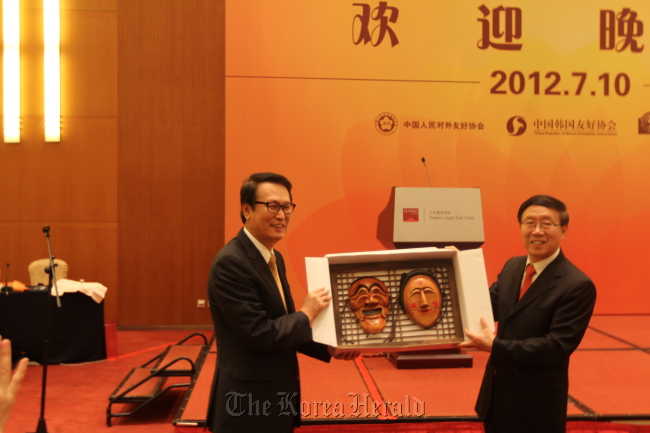 Shin Jung-seung (left), a former Seoul Ambassador to China, presents Korea’s traditional Hahoe masks to Feng Zuoku, vice president of the CPAFFC, during a welcome reception in Beijing on Tuesday.  Future Forest
