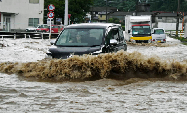 <YONHAP PHOTO-0438> Cars wade through flood water caused by heavy rain in Hita, Oita Prefecture, Japan, Saturday, July 14, 2012. Heavy rain triggered flash floods and mudslides in southern Japan on Thursday, killing nearly two dozens of people. (AP Photo/Oita Godo Shimbun via Kyodo News, Ayako Wada) ONLINE OUT, NO SALES, JAPAN OUT, MANDATORY CREDIT, NO LICENSING IN JAPAN, CHINA, HONG KONG, SOUTH KOREA AND FRANCE/2012-07-14 13:02:38/ <저작권자 ⓒ 1980-2012 ㈜연합뉴스. 무단 전재 재배포 금지.>
Cars wade through flood water caused by heavy rain in Hita, Oita Prefecture on Saturday.  AP-Yonhap News