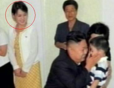 North Korean leader Kim Jong-un (front-center) holds a child during a visit to a Pyongyang kindergarten with an unidentified woman (left)who is speculated to be his wife. (Yonhap News)
