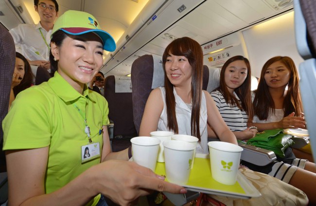 Emily Cho (left), senior vice president of marketing and public relations at Jin Air and the youngest daughter of Korean Air head Cho Yang-ho, serves beverages on a Gimpo-Jeju flight Tuesday.
Yonhap News