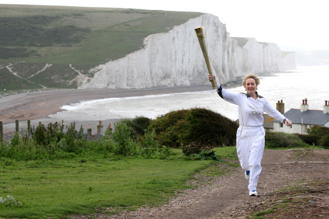 Kathy Gore runs with the Olympic flame in Seaford Head, England, Tuesday.  AP-Yonhap News