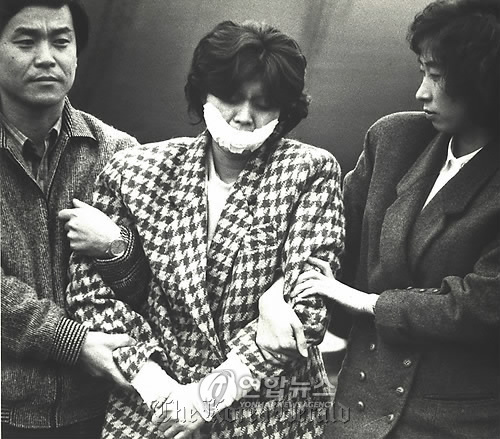 Kim Hyun-hui, a self-confessed North Korean terrorist responsible for the bombing of Korean Air 858, is being transferred under escort at Gimpo International Airport in this file photo taken on Dec. 15, 1987. Yonhap News