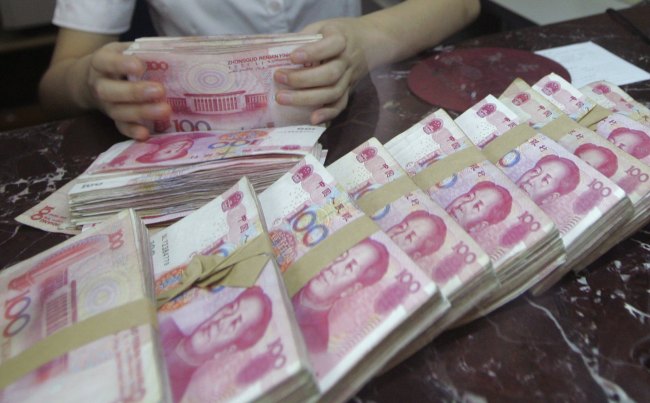 An employee counts 100 yuan banknotes at a branch of Bank of Communications in Shenyang, China.  (Bloomberg)