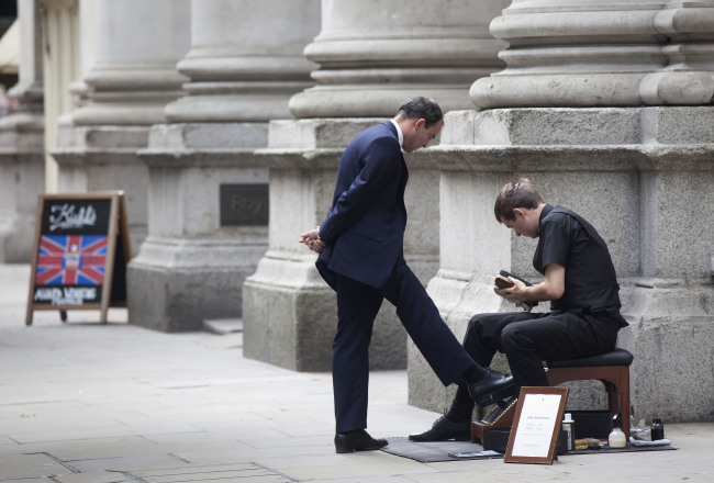A shoe cleaner polishes the shoes of a businessman outside the Bank of England in London.  (Bloomberg)
