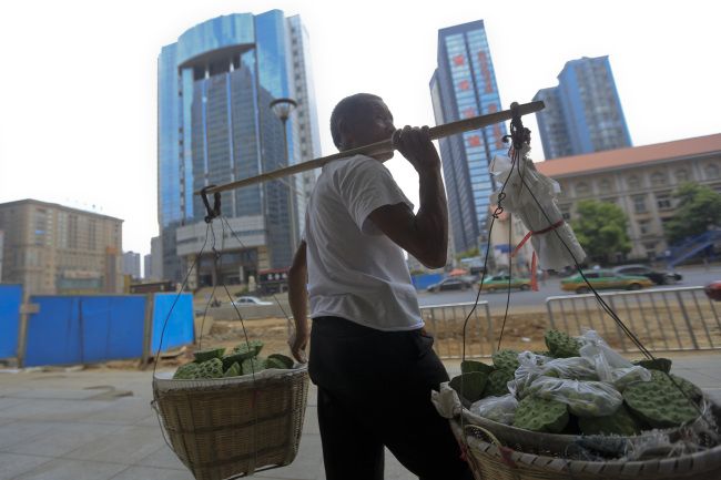 A vendor selling produce stands in downtown Changsha, Hunan Province, China, on Friday, July 13, 2012. Gross domestic product (GDP) expanded 7.6 percent in the second quarter of 2012 from a year earlier, China's National Bureau of Statistics said today in Beijing. Photographer: Nelson Ching/Bloomberg
A vendor selling produce stands in downtown Changsha, China.  Bloomberg