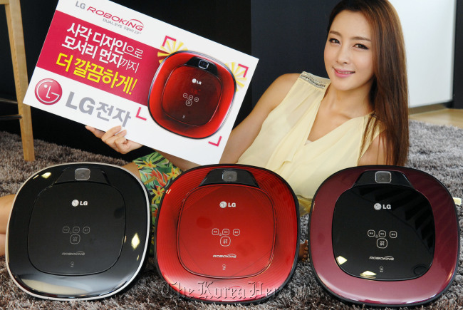 A model features LG Electronics’ new square-shaped automated robotic vacuum cleaner called “Roboking Dual Eye 2.0” in downtown Seoul on Sunday. LG Electronics