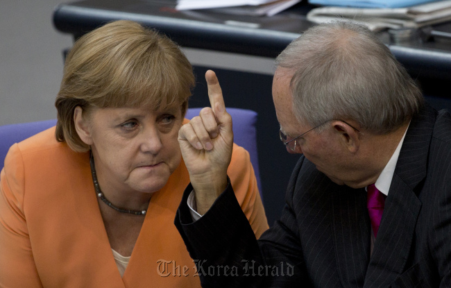 German Finance Minister Wolfgang Schaeuble (right) gestures as he speaks to German Chancellor Angela Merkel, during a special session of the German Parliament Bundestag in Berlin.  AP-Yonhap News