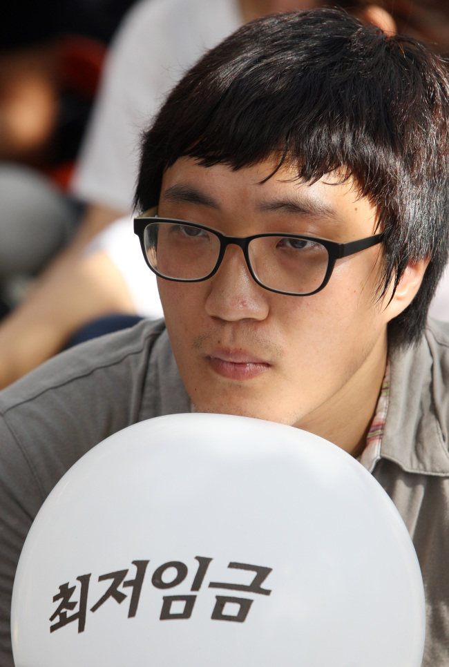 A young man holds a balloon with “minimum wage” written on it in a rally in front of the National Assembly in Yeouido, Seoul, on Tuesday, demanding an increase in this year’s minimum wage.
Yonhap News