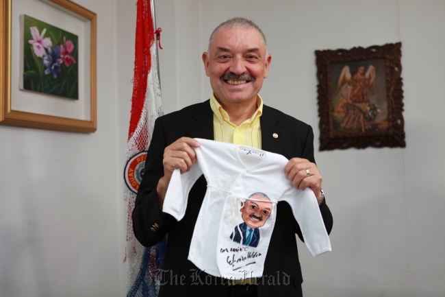 Paraguayan Ambassador Ceferino Valdez holds up clothes which will go to infants in need after the Benet Chogori Campaign named him an honorary ambassador in Seoul on Wednesday. Korea Sarangbat Society