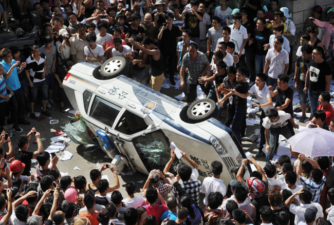 Local residents push over a police vehicle as they gather to protest against plans for a water discharge project in Qidong, China Saturday.  AP-Yonhap News
