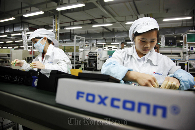 Employees work on the assembly line at Hon Hai Group’s Foxconn plant in Shenzhen, Guangdong province, China.  Bloomberg