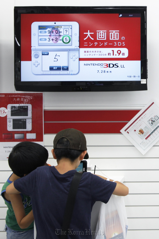 Boys try out Nintendo Co.’s 3DS LL handheld game console at a Yamada Denki Co. electronics store in Tokyo on Saturday.  Bloomberg