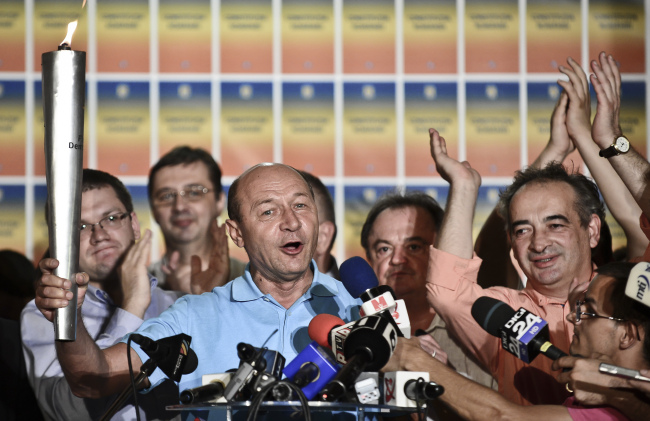 Suspended Romanian President Traian Basescu holds a torch while speaking at the end of the referendum on his possible impeachment in Bucharest on Sunday.  AP-Yonhap News