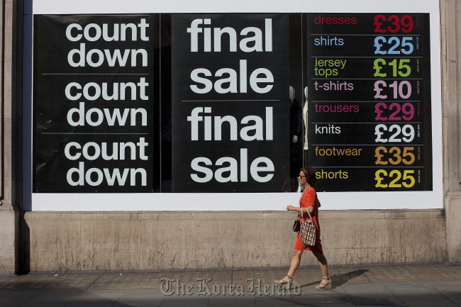 A pedestrian passes a final sale poster advertising discounted goods for sale on Regent Street in London.  Bloomberg