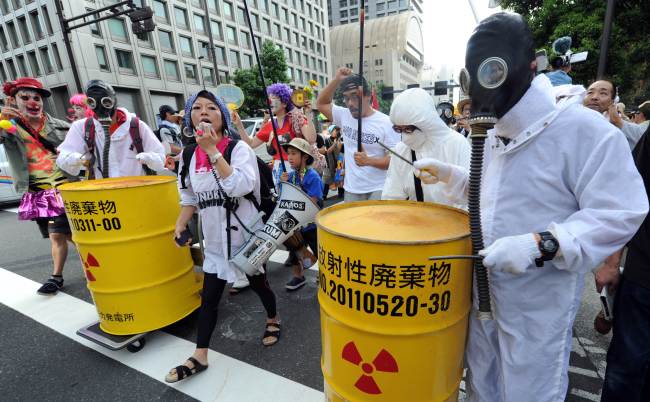 Protesters wearing gas masks and white costumes, similar to those of decontamination workers at the crippled Fukushima plant, beat drums painted with radioactive waste symbols during an anti-nuclear power demonstration in Tokyo on Sunday.  AFP-Yonhap News