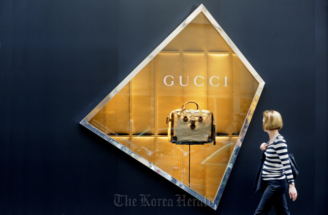 A pedestrian passes a window display for Gucci, owned by PPR SA, at the Le Printemps department store in Paris.   Bloomberg