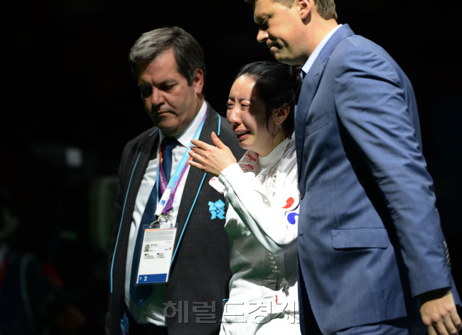 2012 런던올림픽 펜싱대표팀의 신아람이 30일 런던의 엑셀 런던의 사우스 아레나에서 열린 여자 에페 준결승에서 브리타 하이데만(독일)과 연장까지 가는 접전을 펼친 끝에 석연치 않은 판정으로 패한 뒤 경기가 진행된 코트에 주저 앉아 재심을 기다리던 중 관계자들에게 코트 밖으로 이끌리며 눈물을 쏟고 있다. 이날 경기는 1초를 남겨둔 상황에서 하이데만이 마지막 3번의 공격을 하는 동안 1초의 시간이 흐르지 않아 논란을 남겼고, 한국팀은 30여분 동안 강력히 항의했지만 결국 받아들여지지 않았다. 120730 런던=올림픽사진공동취재단j
2012 런던올림픽 펜싱대표팀의 신아람이 30일 런던의 엑셀 런던의 사우스 아레나에서 열린 여자 에페 준결승에서 브리타 하이데만(독일)과 연장까지 가는 접전을 펼친 끝에 석연치 않은 판정으로 패한 뒤 경기가 진행된 코트에 주저 앉아 재심을 기다리던 중 관계자들에게 코트 밖으로 이끌리며 눈물을 쏟고 있다. 이날 경기는 1초를 남겨둔 상황에서 하이데만이 마지막 3번의 공격을 하는 동안 1초의 시간이 흐르지 않아 논란을 남겼고, 한국팀은 30여분 동안 강력히 항의했지만 결국 받아들여지지 않았다. 120730 런던=올림픽사진공동취재단j