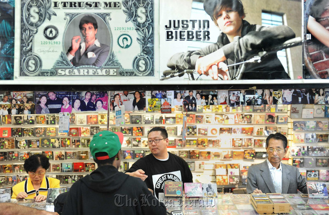 From right: Kim Wan-joon, his son Kirk and his wife Boo-ja work behind the counter of their music store stall at the Compton Fashion Center swap meet in Compton, California, on June 18.   Los Angeles Times/MCT