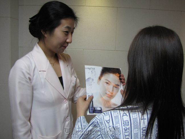 Clutching a picture of her favorite Korean actress, whom she aims to resemble, a patient prepares for nose surgery at a plastic surgery clinic in Seoul.   MCT
