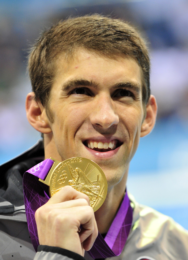 Michael Phelps of the United States shows off his Gold Medal following the medal ceremony after the Men’s 200-meter Individual Medley final on Thursday.   UPI-Yonhap News