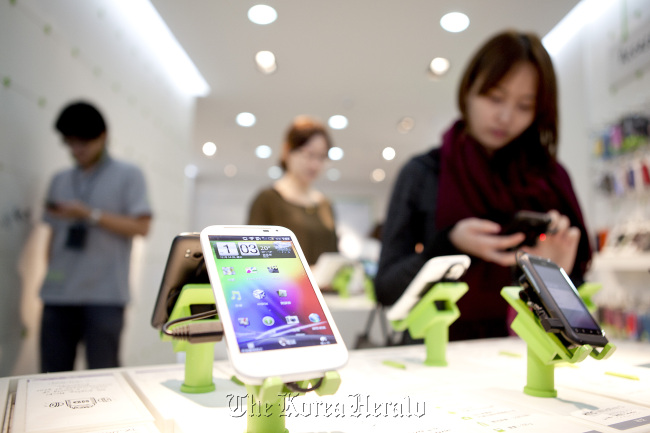 Visitors try out HTC Corp. mobile handset devices near an HTC Sensation XL, in foreground, at an HTC store in Taipei.  Bloomberg