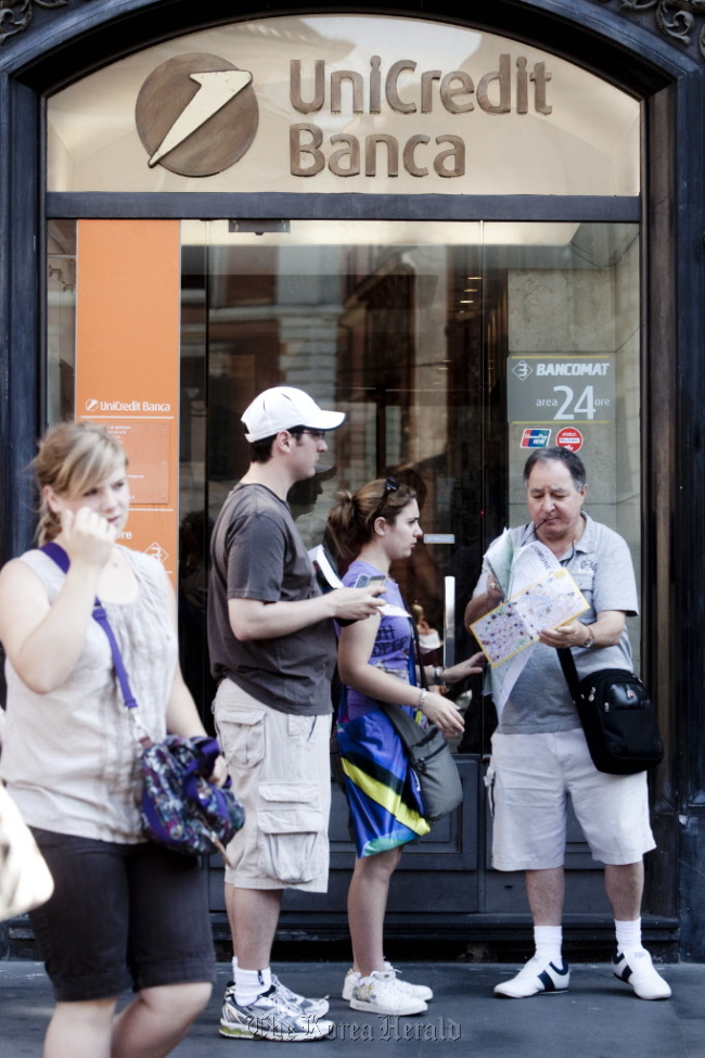 Tourists stand outside a UniCredit SpA branch in Rome.   Bloomberg