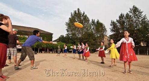 Participants of 2011 Pyongyang Ultimate Tournament throw frisbees with North Korean school children.  Courtesy of Sam Baker