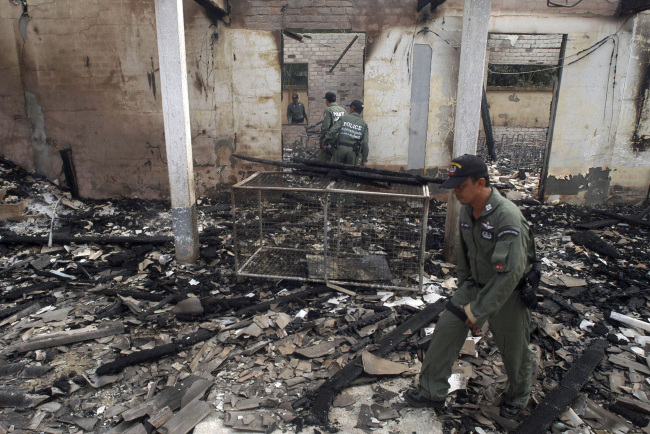 Thai police officers examine the charred Guwing school building after it was burnt down by suspect Muslim separatists in Mayor district of Pattani province, southern Thailand, Aug. 2.  AP-Yonhap News
