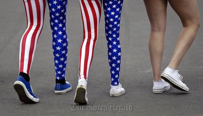 Nick Miller (left) and his sister Kendall Miller (center) from San Francisco wear leotards in the colors of the United States national flag as they walk with a friend through London’s Olympic Park on Aug. 2. AP-Yonhap News