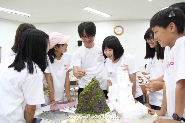 Sculptor Lee Wan (center) gives advice to junior artists participating in the annual art camp supported by K-Auction and Mecenat Council on Wednesday at a training center in Seoul.    Mecenat Council