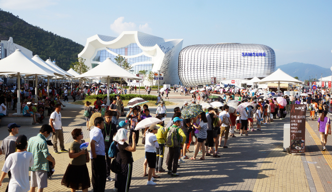 Visitors to the 2012 Yeosu Expo line up in front of a pavilion despite the blistering heat on Tuesday.  (Yonhap News)