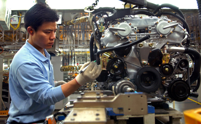 An employee assembles the engine of a vehicle on the production line at the Renault Samsung Motors' factory in Busan in a file photo. (Bloomberg)