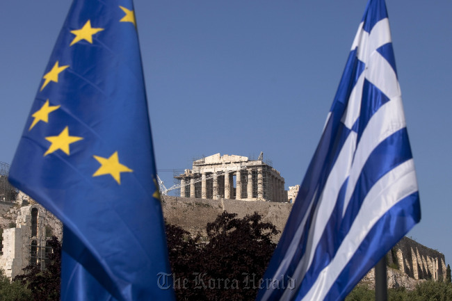 A European Union flag (left) hangs beside a Greek national flag beneath the Parthenon temple in Athens.  Bloomberg