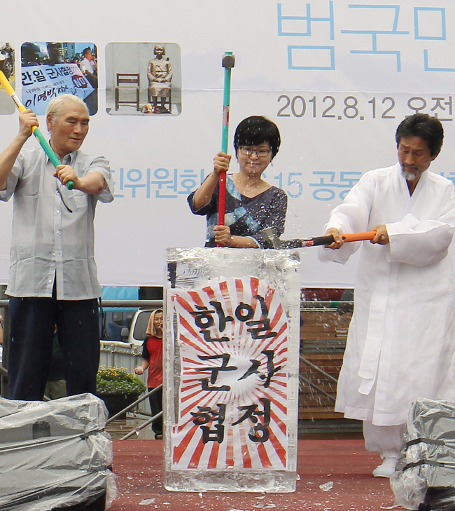 Unified Progressive Party chairman Kang Ki-kab (right) and members of non-governmental organizations hammer at a block of ice carrying a banner that reads “Korea-Japan military agreement” at a rally in Seoul on Sunday. Yonhap News