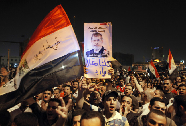 Thousands of supporters celebrate with a poster showing Mohammed Morsi in Tahrir Square, in Cairo, late Sunday.   AP-Yonhap News