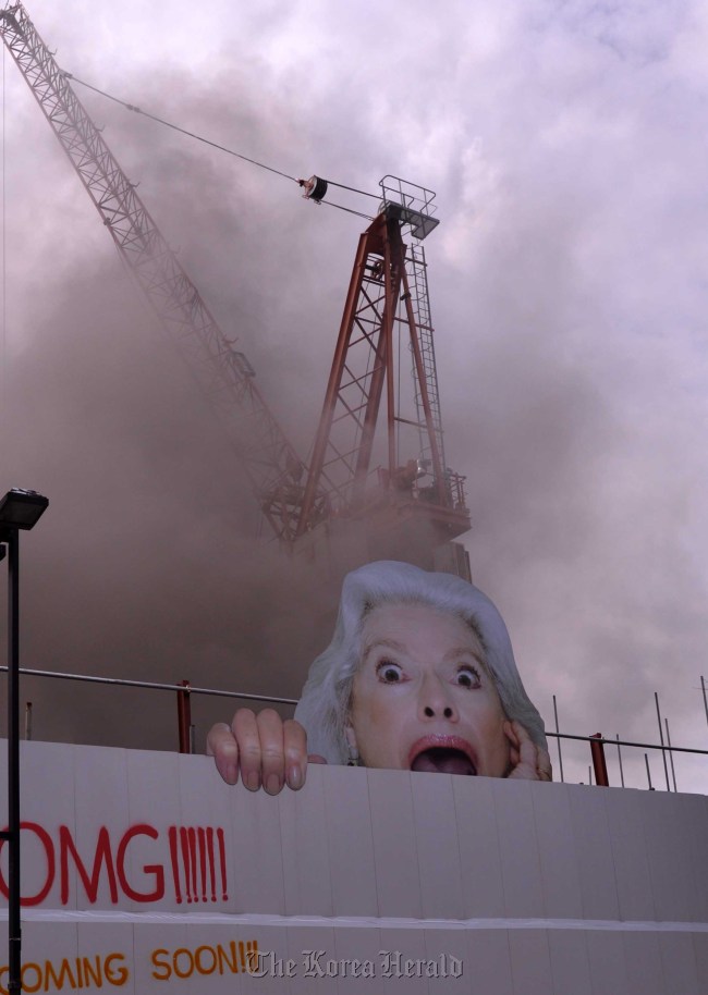 Workers wait to be rescued at the top of a crane after a fire broke out at the construction site for the National Museum of Contemporary Art in Seoul on Monday.  Lee Sang-sub/The Korea Herald