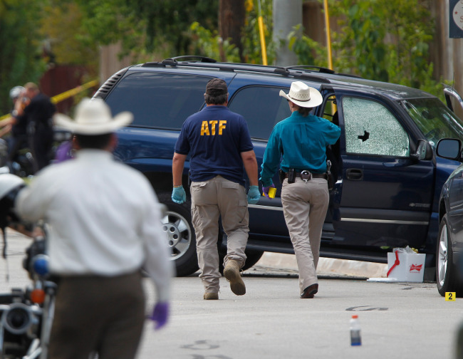 ATF and other investigators walk near a vehicle which was struck by a bullet near the scene where a gunman opened fire near the Texas A&M university in College Station, Texas, Monday.   AP-Yonhap News