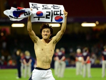 South Korean soccer player Park Jong-woo carries a sign given by a fan that reads “Dokdo Is Our Territory,” after winning the bronze medal match against Japan at the 2012 London Olympics on Friday. The IOC banned him from the medal ceremony for displaying a political message at the match. ( Ahn Hoon/The Korea Herald)