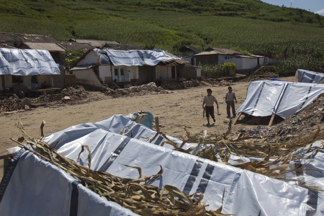 Displaced North Korean women, left homeless by July flooding, walk among temporary tents set up in their destroyed neighborhood in Ungok, North Korea on Monday. Floods killed at least 169 North Koreans nationwide and destroyed tens of thousands of homes.   AP-Yonhap News